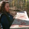 Christi (Kelsey Kaufmann) holds the Camp Blood sign in CAMP BLOOD FIRST SLAUGHTER from Polonia Brothers / Sterling Entertainment.